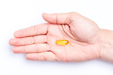 Close up yellow soft gel capsule in male hand with white background, concept of essential oil supplement intake.