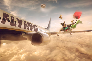 Woman flying in the wing of a moving plane, over clouds with luggage, lowcost holiday