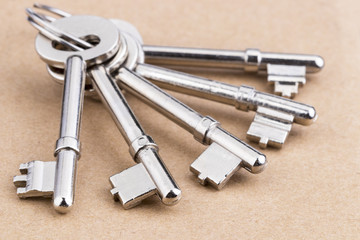 Old silver-color metal keys with key chain on wooden background