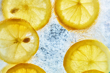 Lemon on the ice. Refreshing summer background of citrus. Yellow lemons and ice. Top view.