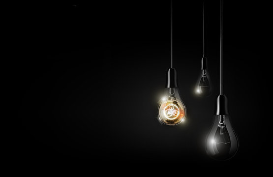Glowing abstract futuristic light bulb is hanging between a lot of turned off light bulbs on dark black background, copy space, vector illustration