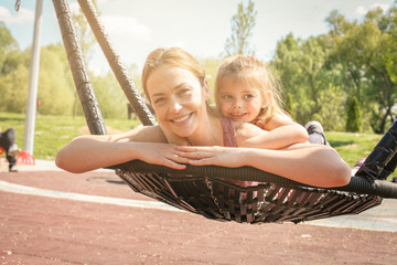 Mother and daughter playing on the swing.