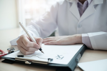 Medicine doctor hand writing something on medical from. Medical care, insurance, prescription, paper work or career concept with vintage tone.