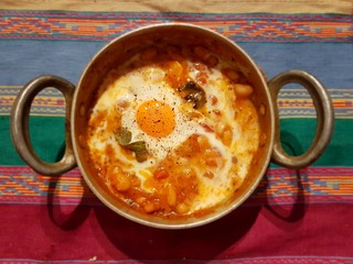 Beans and fried eggs in copper pot