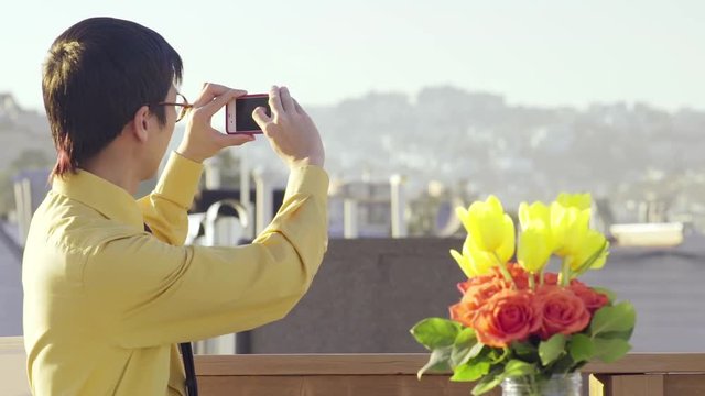 Multi-Ethnic Man On A Roof, Turns To Take A Photo Of The City View Behind Him