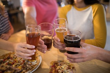 Cropped hands of friends toasting drinks in restaurant