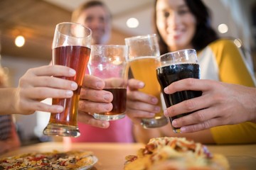 Low angle view of happy friends toasting drinks in restaurant