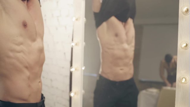 Crop man taking off shirt