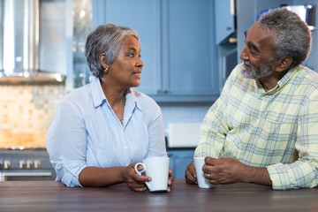 Couple talking while having coffee in kitchen