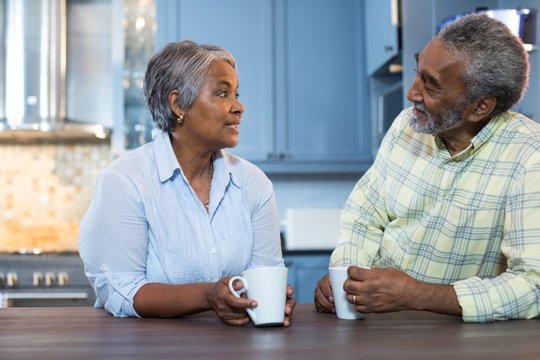 Couple Talking While Having Coffee In Kitchen