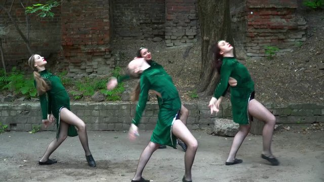 Women in green costumes dancing on the street near the tree