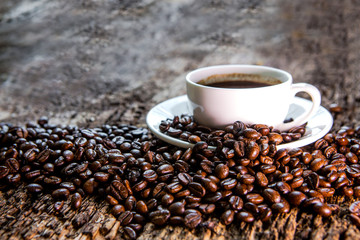 Hot Coffee cup and roast coffee beans on a wooden table. Dark background