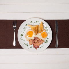 Plate of breakfast with fried eggs, bacon and toasts isolated on white background