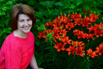 Naklejka premium Woman near flower bed with orange lilies