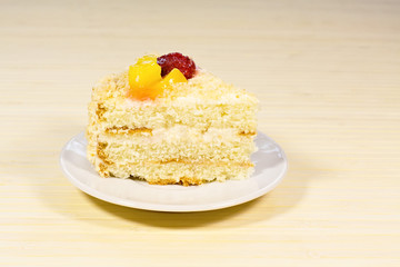 Sliced tasty cake with straberry and peach on wooden background