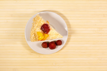 Sliced tasty cake with straberry and peach on wooden background