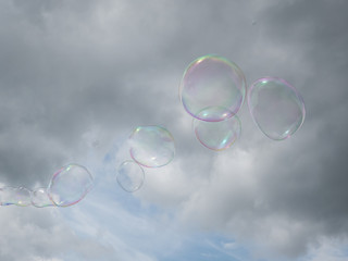 Colorful soap bubbles in front of a cloudy blue sky