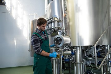 Fototapeta na wymiar Male worker taking beer from storage tank at factory