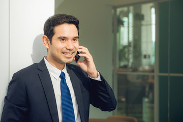 Handsome businessman in suit speaking on the phone in office.