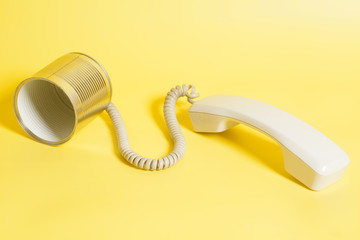 Tin can phone with handset on yellow background