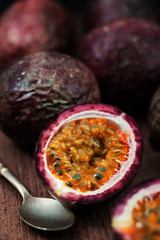Red passion fruits and slice with  spoon on wood background.