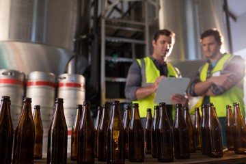 Close up of beer bootles with coworkers discussing in background - Powered by Adobe