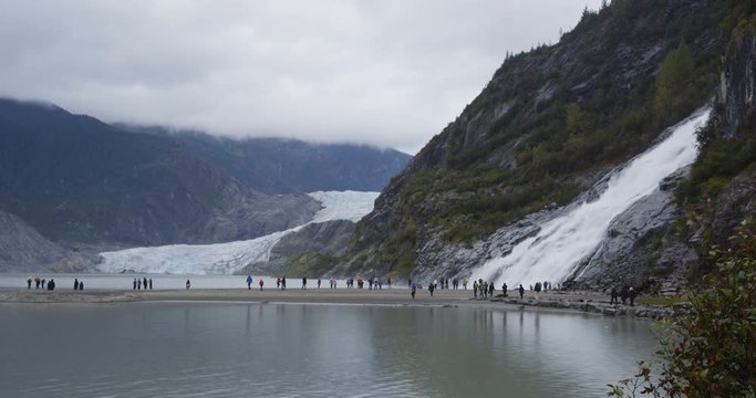 Alaska glacier landscape - tourists visiting Mendenhall Glacier tourist attraction. People in front of famous cruise shore excursion near Juneau. Nugget Falls waterfall on right. TIME-LAPSE.
