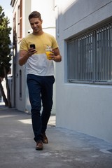 Young man having juice while using mobile phone