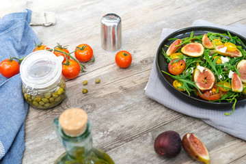 preparing easy diet salad with fig, some herb and tomato on rustic wooden table.  Delicious fruity
