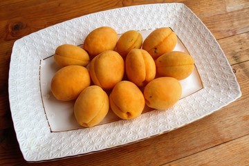 Fresh apricots are a group and individually on the plate and in a human hand.