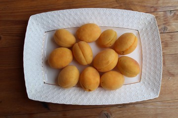 Naklejka na ściany i meble Fresh apricots are a group and individually on the plate and in a human hand.