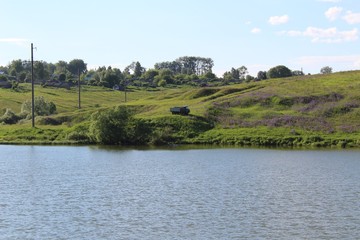 Lake in good weather. On the opposite bank is a truck on which fishermen arrived. The coast is covered with thickets of lupines.