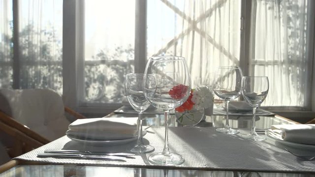Dining table under sunlight. Empty wineglasses and flower vase. Restaurant business ideas.