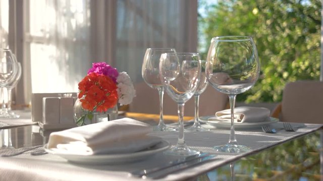 Dining table with flower vase. Empty shiny wineglasses.