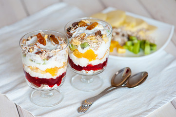 Delicious healthy dessert with cottage cheese, raspberry jam, fruit and muesli on a wooden background