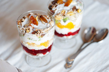 Delicious healthy dessert with cottage cheese, raspberry jam, fruit and muesli on a wooden background