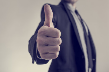 Toned image of businessman showing a thumbs up sign towards you