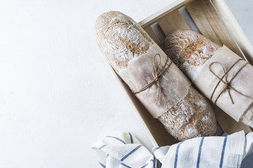Homemade bread in a wooden box on a white concrete background