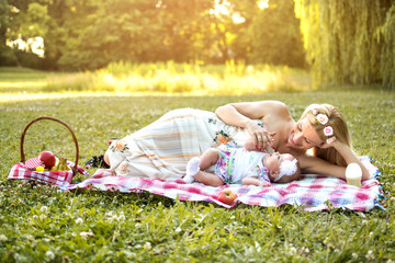 Young mother with her little baby having picnic in the park.