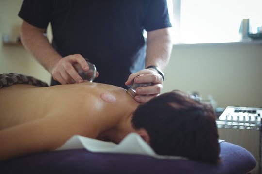 Therapist giving cupping therapy to man at spa