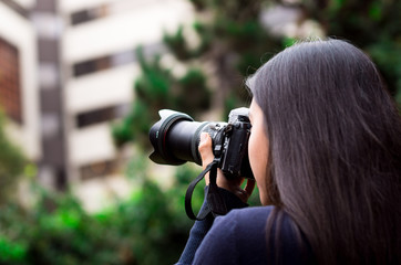 Young woman stalking and taking pictures with her camera, at outside with a office background