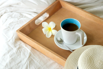 coffee cup in wood tray on the bed background in the morning time.
