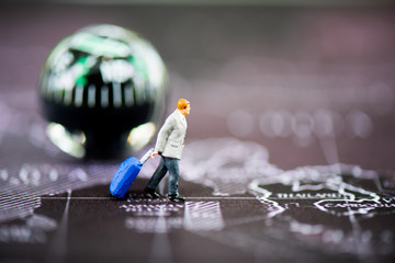 miniature people: businessman hold the suitcase walking on the world map with a compass on...