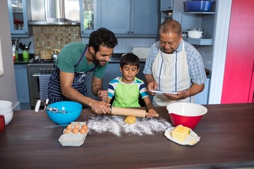 Father assisting son for preparing food while standing by man us