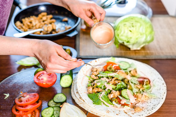 Fast food cooking. Hands preparing tortilla wrap with chicken and vegetable salad, kebab gyros...