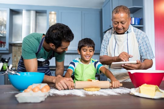 Smiling man using table while standing by father and son prepari