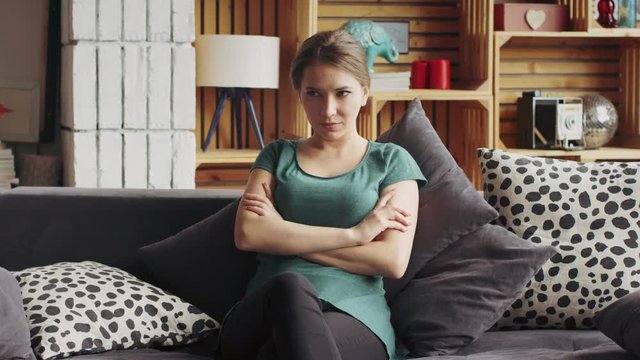 Beautiful girl sitting on the couch in the living room. She's in a bad mood and upset with her boyfriend