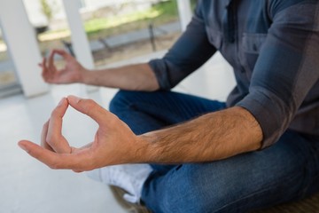 Businessman meditating while sitting on floor at office