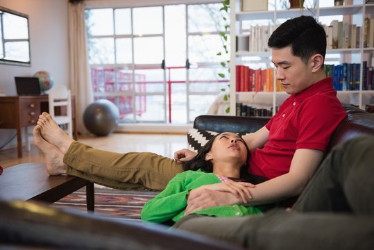 Couple interacting while relaxing on sofa in living room