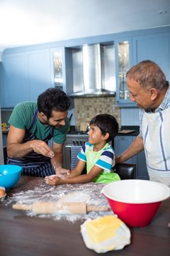 Happy father sprinkling flour on son hand while preparing food w